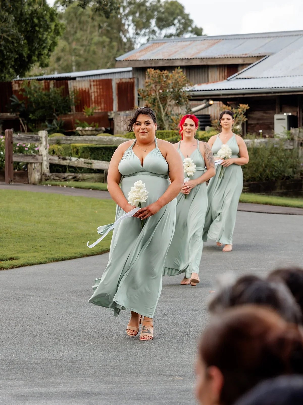 Bridesmaids in sage green dresses walking down the ceremony aisle — Sean Reefman Photography