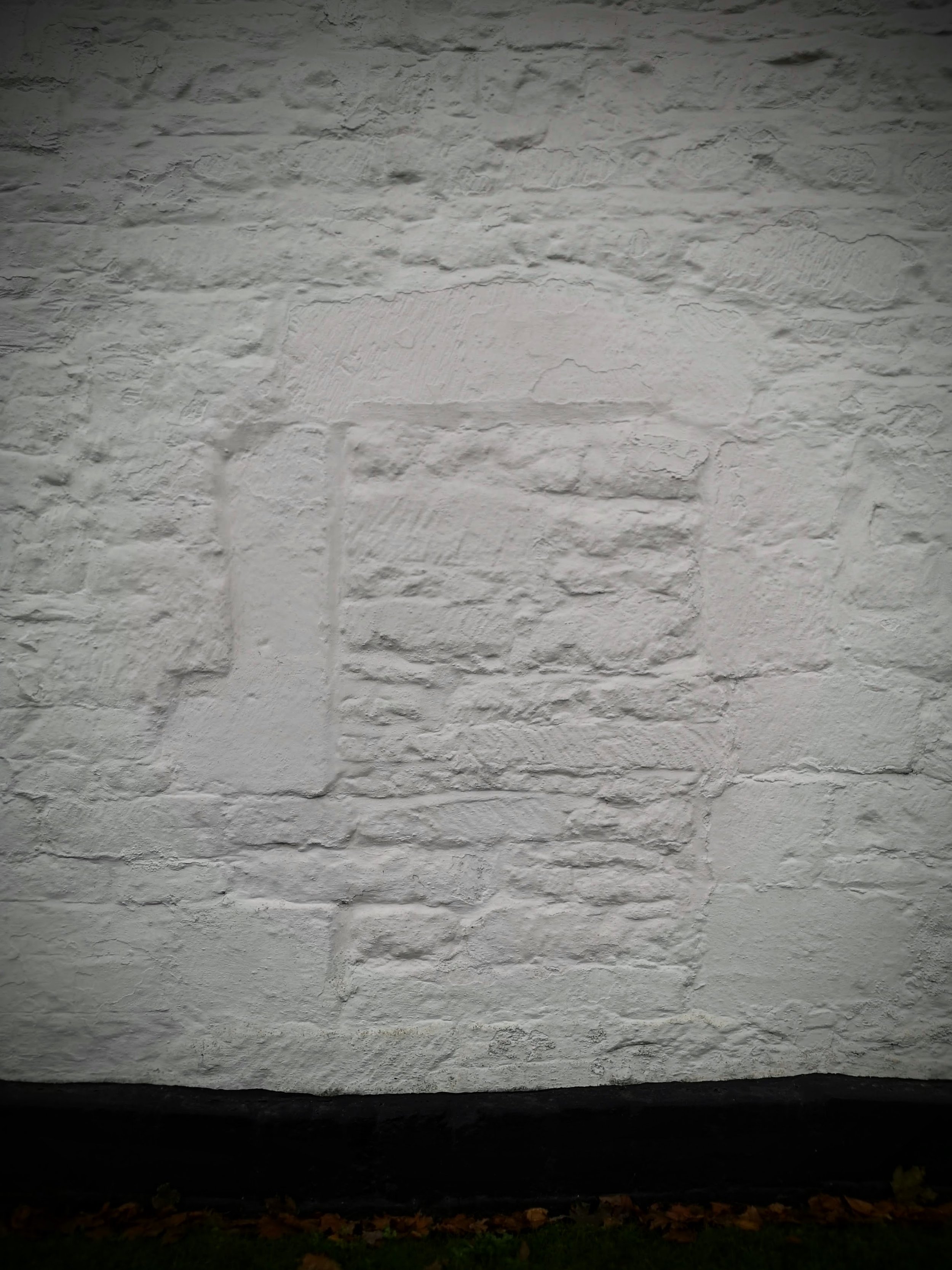 White brick wall with a partially covered or painted brick pattern.