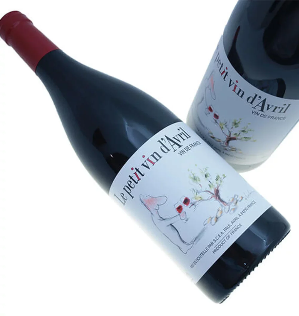 A bottle of red wine labeled "Le petit vin d'Avril" with a matching wine glass on the label, featuring a hand-drawn illustration of a wine bottle, an olive branch, and grapes.