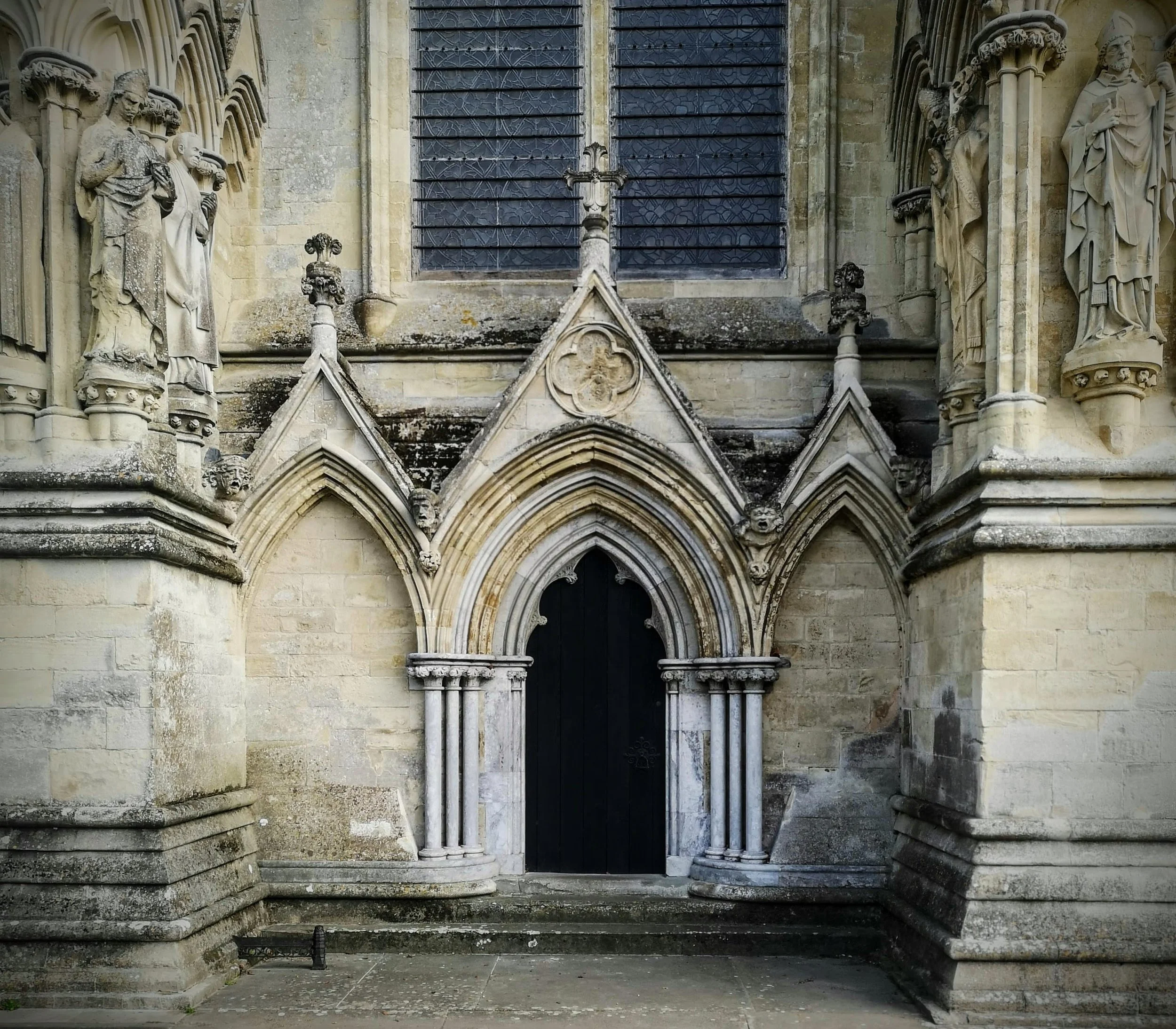 Close-up of an ornate Gothic church entrance with intricate stone carvings and statues surrounding the arched doorway.