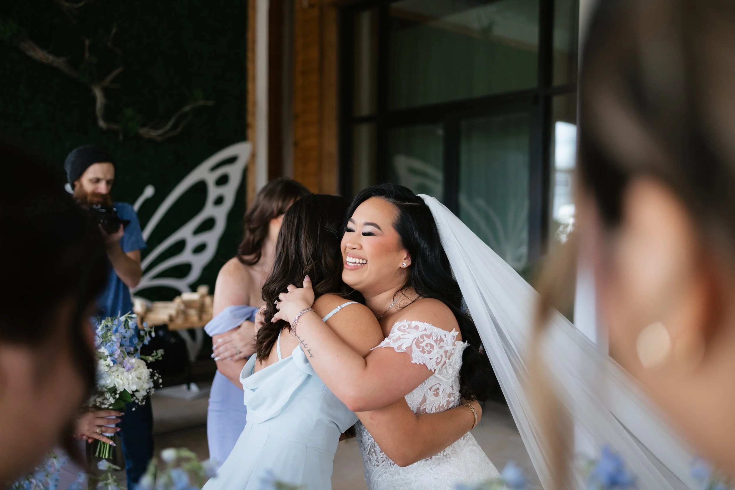 A bride in a wedding dress with two women and a man walking through a doorway, seen from inside a building.