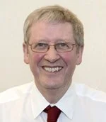 Man with glasses, smiling, wearing a white shirt and red tie
