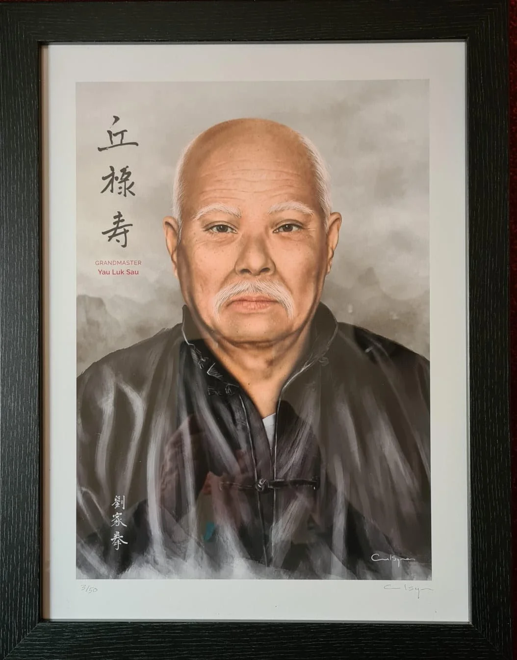 Framed portrait of an elderly man with a bald head, white facial hair, and wearing a black jacket, with Chinese characters, English text reading 'Grandmaster Yau Luk Sau,' and a signature at the bottom.