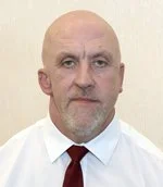 Bald man with a serious expression, wearing a white shirt and dark red tie