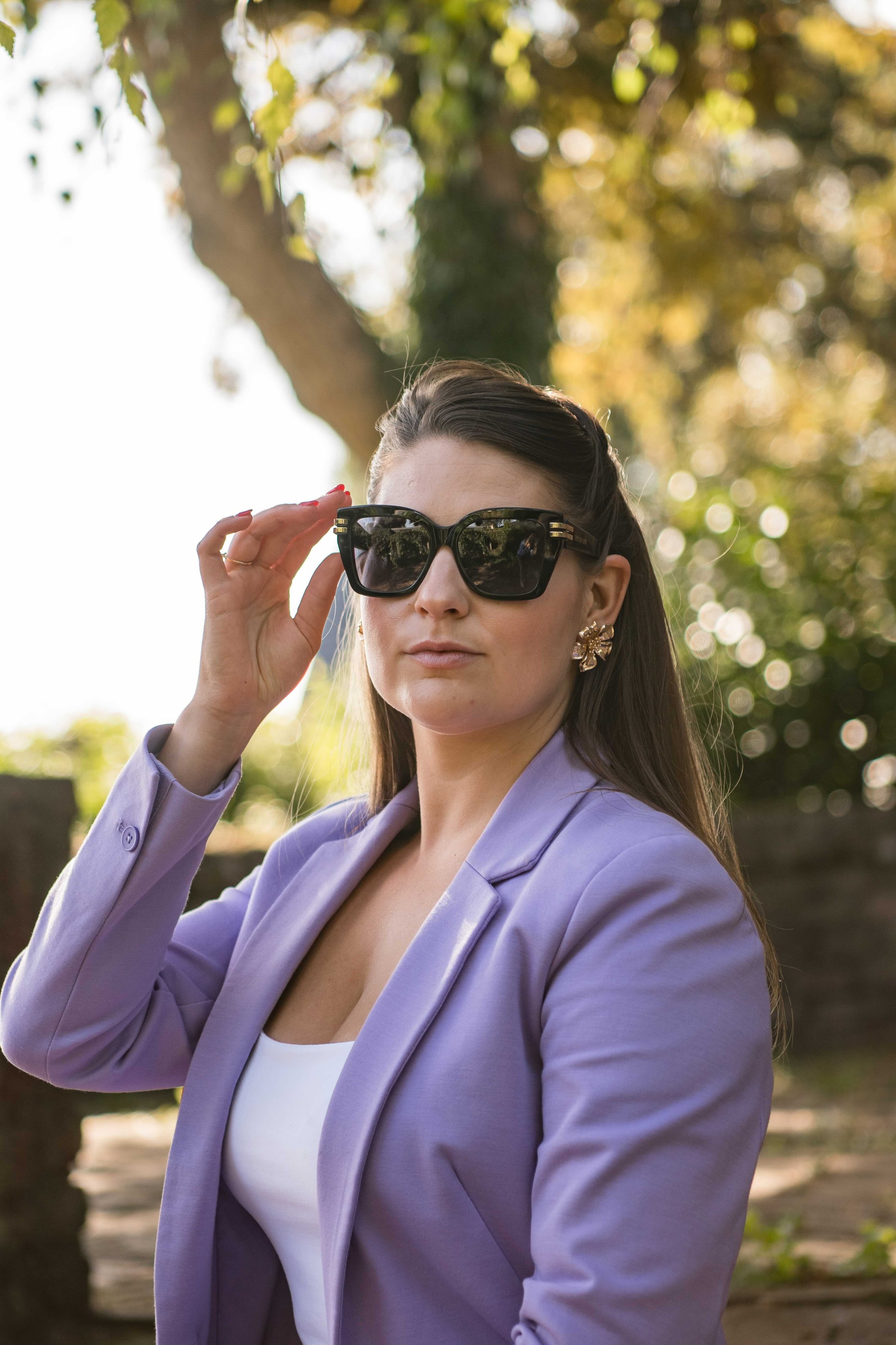 Laura draagt een zonnebril van Dior. De locatie is in Rhenen dicht bij de Rijn en er staat een boom in de achtergrond.