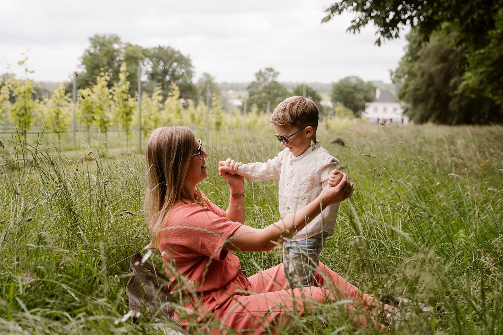 Een moeder die met haar zoon in het gras speelt in de omgeving van Rhenen. Beide dragen ze een zonnebril van House of Glasses.