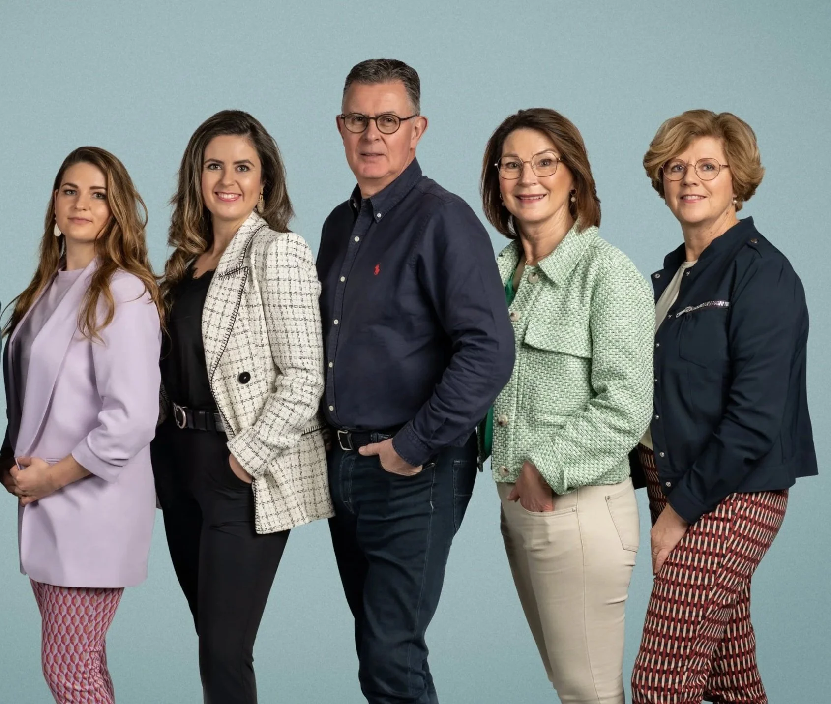 Vijf mensen het team van House of Glasses staan zij aan zij tegen een lichtblauwe achtergrond, gekleed in zakelijke en casual kleding.