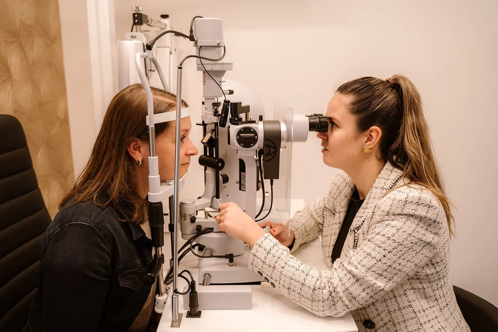 Een opticien voert een oogonderzoek uit op een vrouw met behulp van een speciale apparatuur in een brillenwinkel.