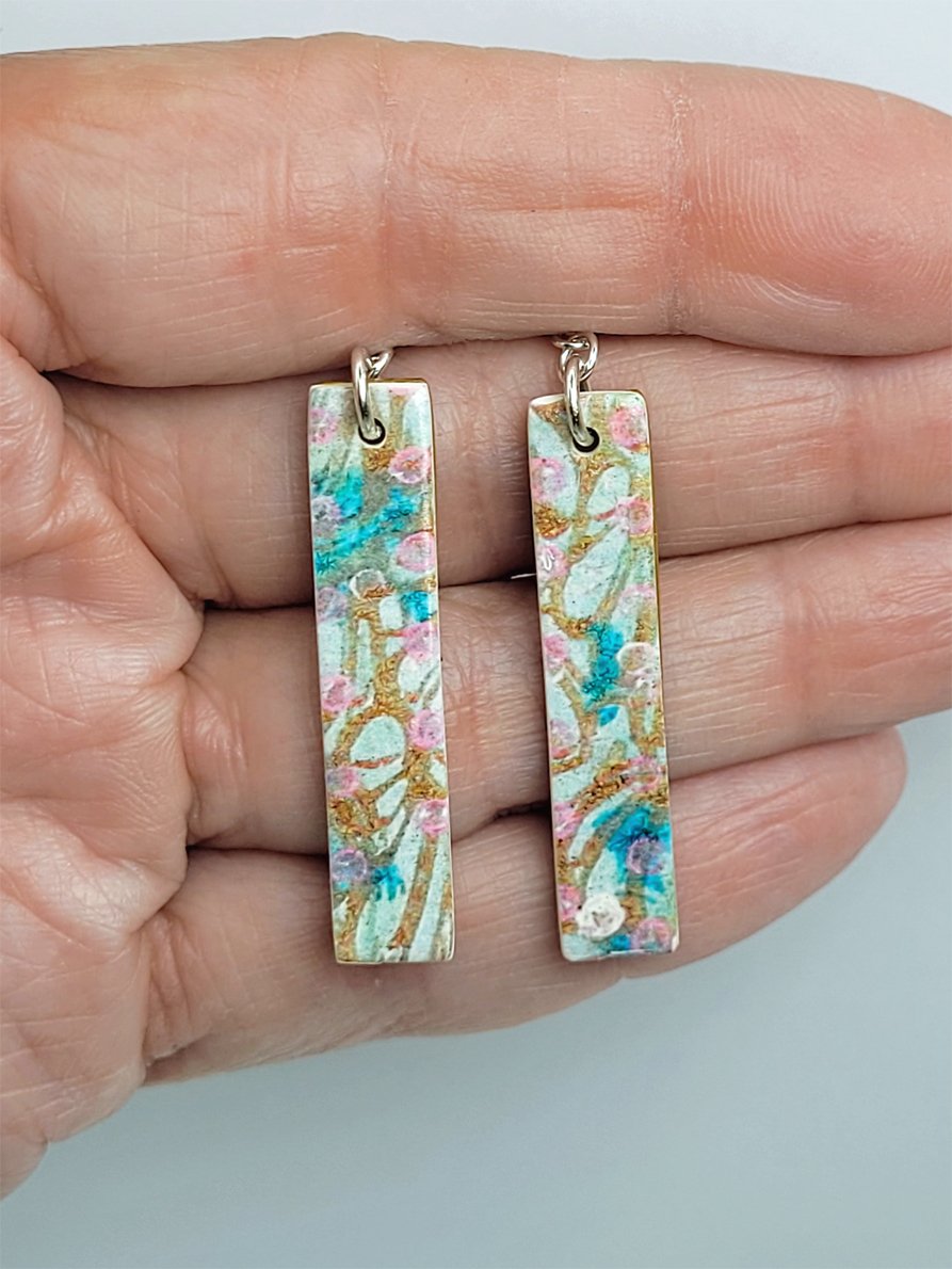 Sprig Ginger Cane long rectangular earrings held in a hand, illustrating their size and pattern detailing.