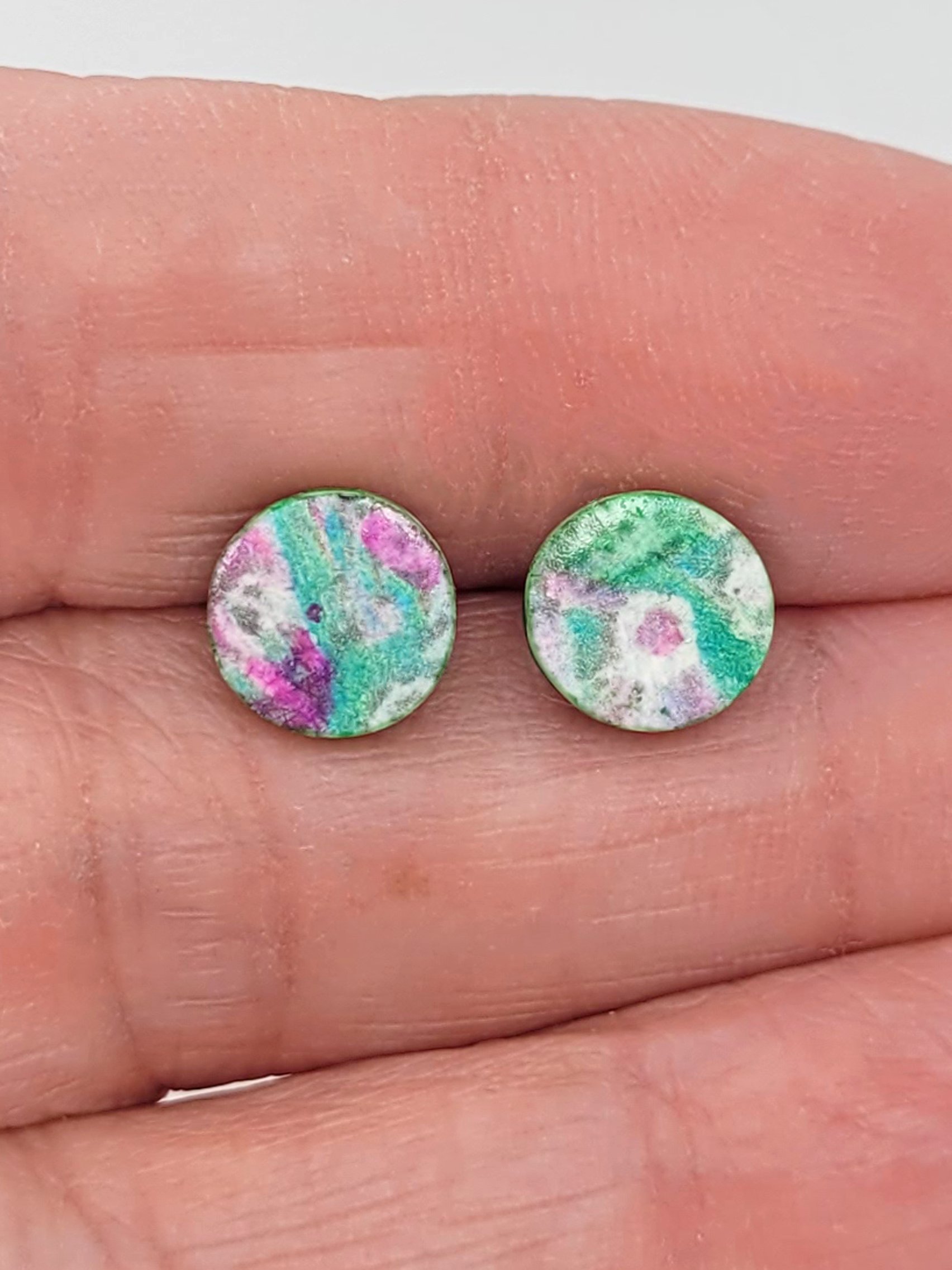 Sprig Green Studs held between fingers to highlight their size.