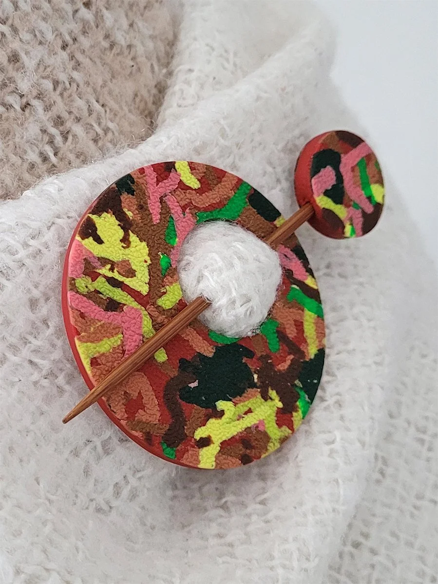 Terracotta Ticker Tape polymer clay Shawl Pin shown from the left edge, pinned to a cream and brown shawl.