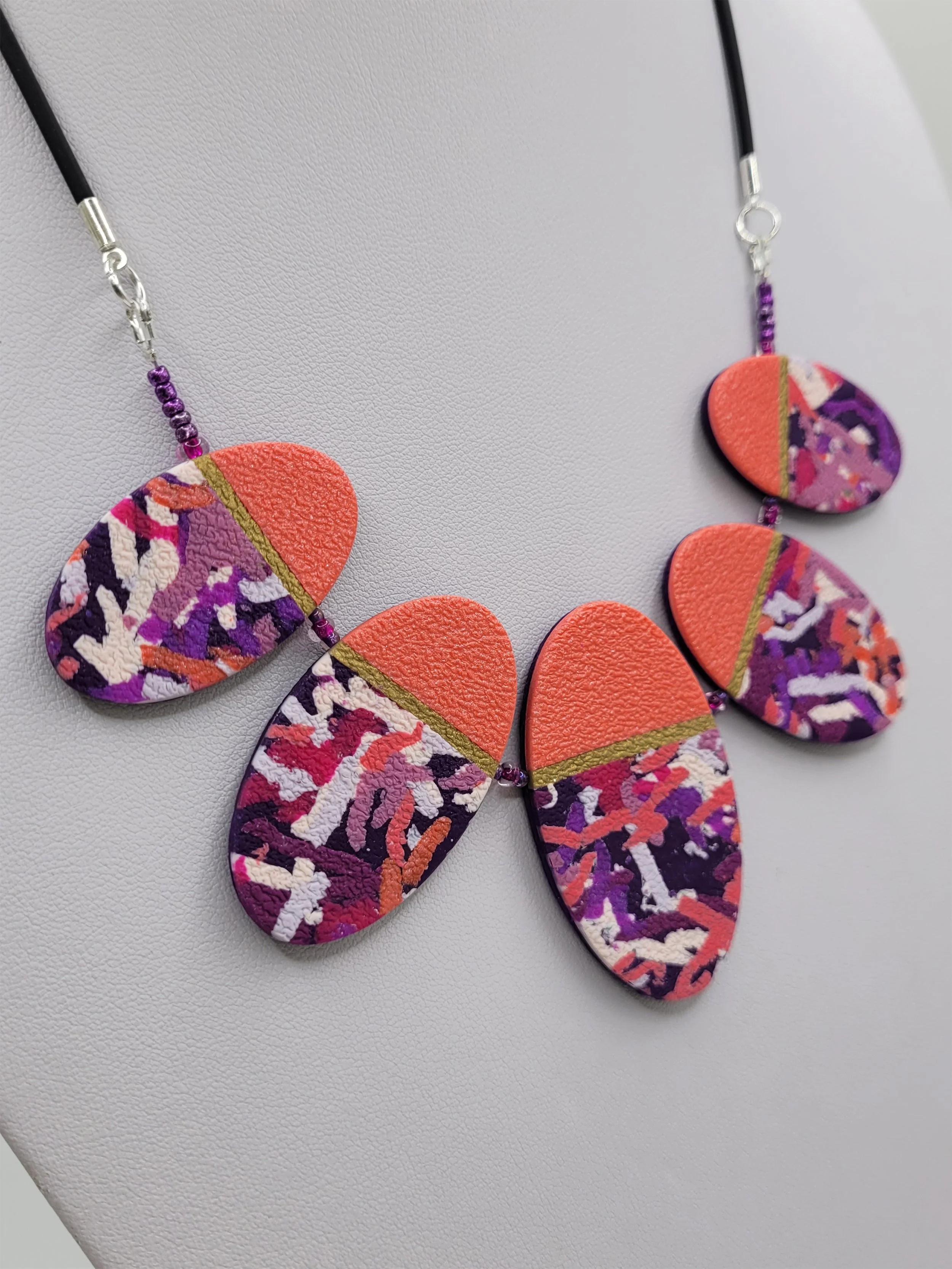 Left edge view of the necklace showing the profile of the oval beads and cord detail.