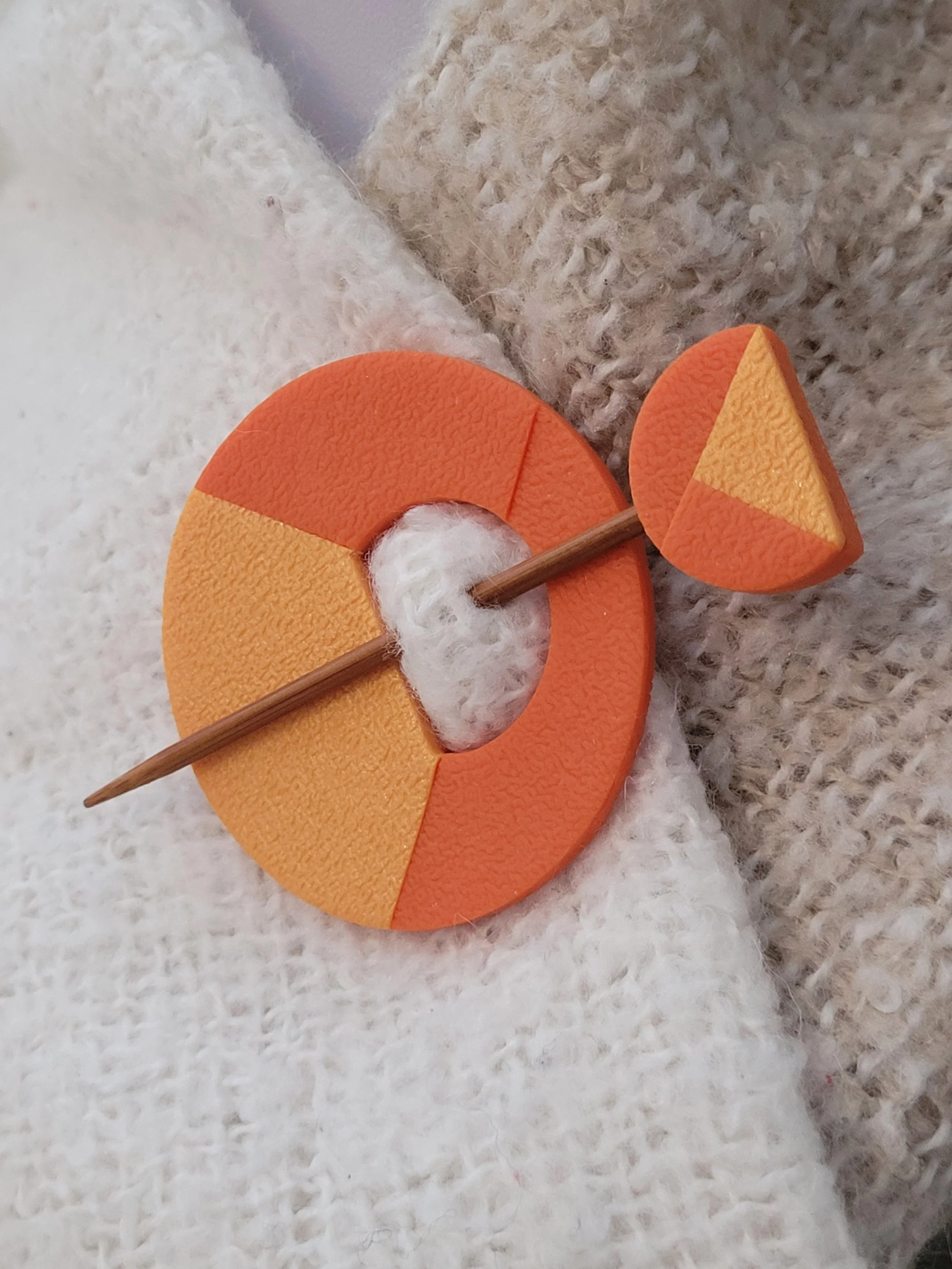 The decorative orange pin head features a geometric half circle with a pearlescent triangular accent.