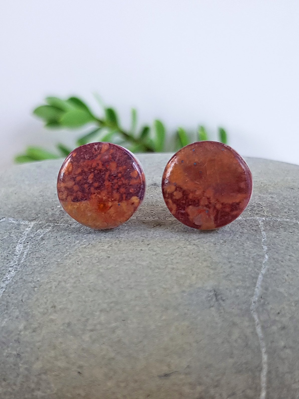 Lightweight polymer clay stud earrings with a hand painted splatter pattern in brown, purple, gold, and bronze with a gloss shine.