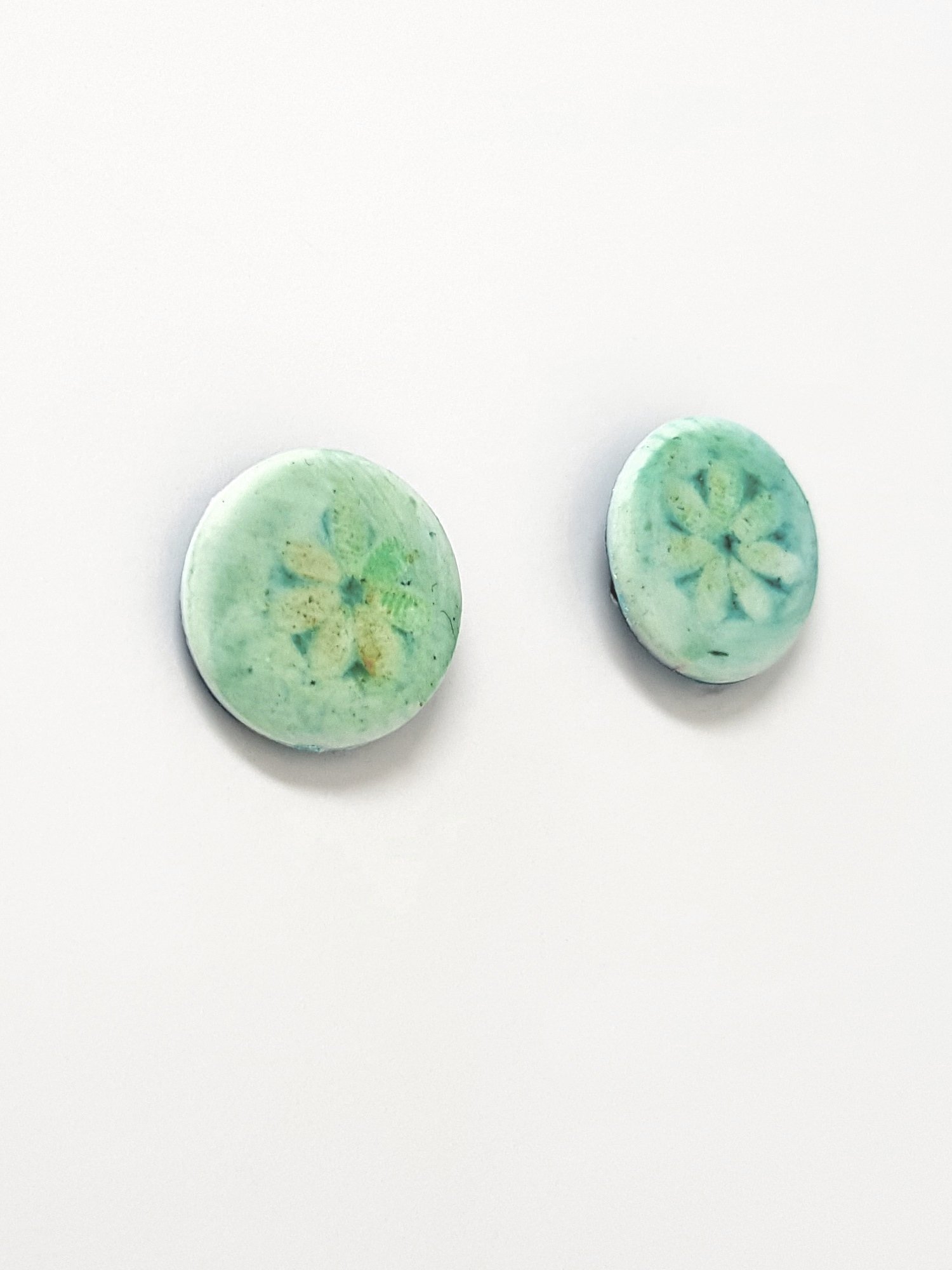 Round polymer clay stud earrings with single turquoise daisy flower motif which fades at the edges.