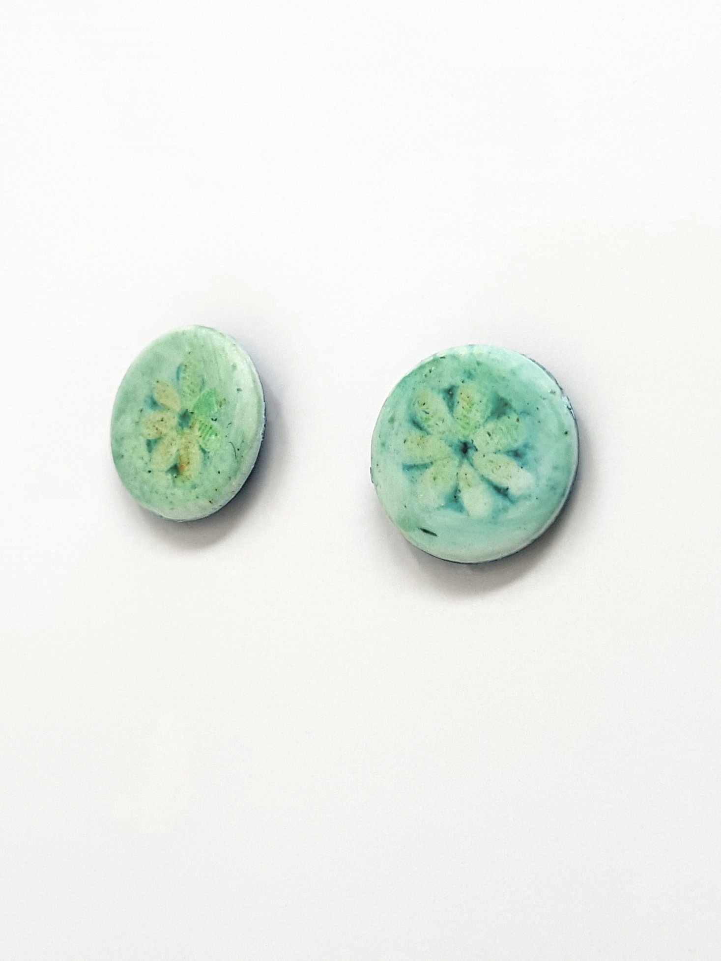 Blue, green, white flower on round polymer clay stud earring.Round polymer clay stud earrings with single turquoise flower motif which fades at the edges.