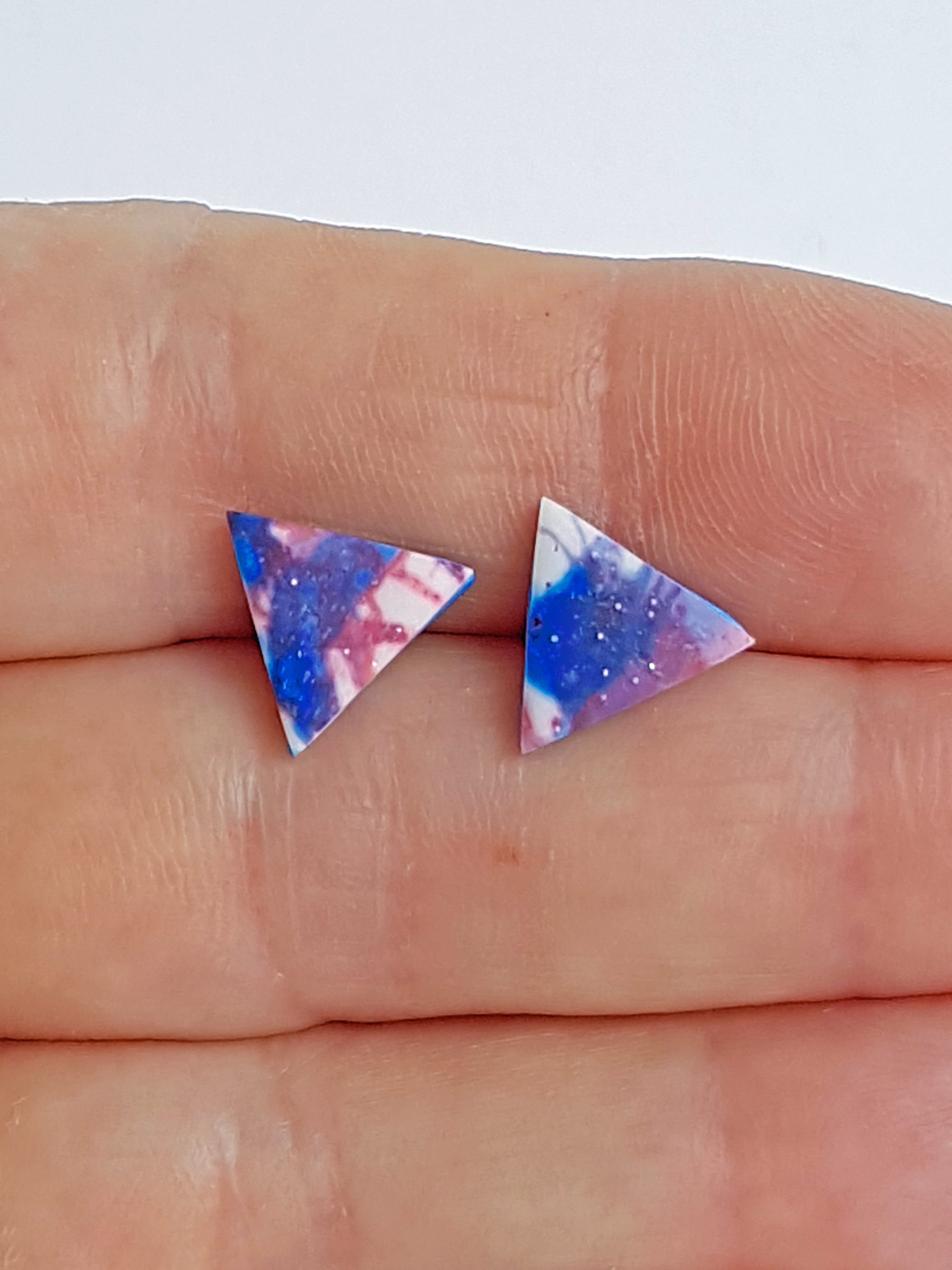 Red, white and blue triangle studs held between fingers to indicate size.