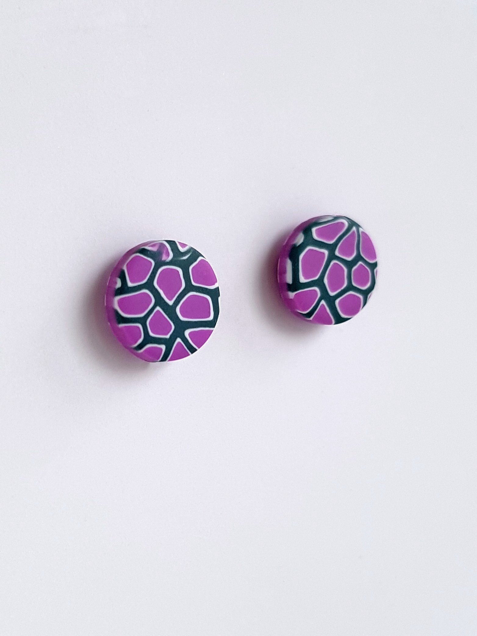 Stud earrings with a pattern of small irregular lilac shapes with white and grey borders.