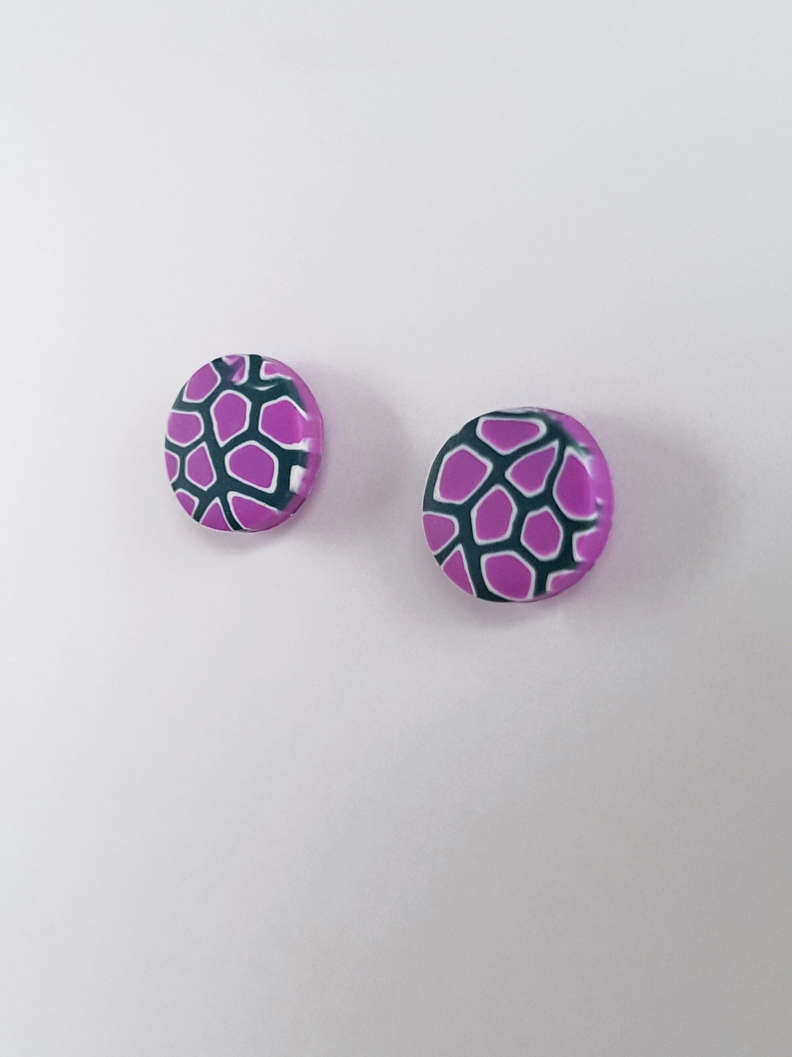 10 mm round, polymer clay stud earrings with a small scale abstract pattern in lilac, white and dark grey.