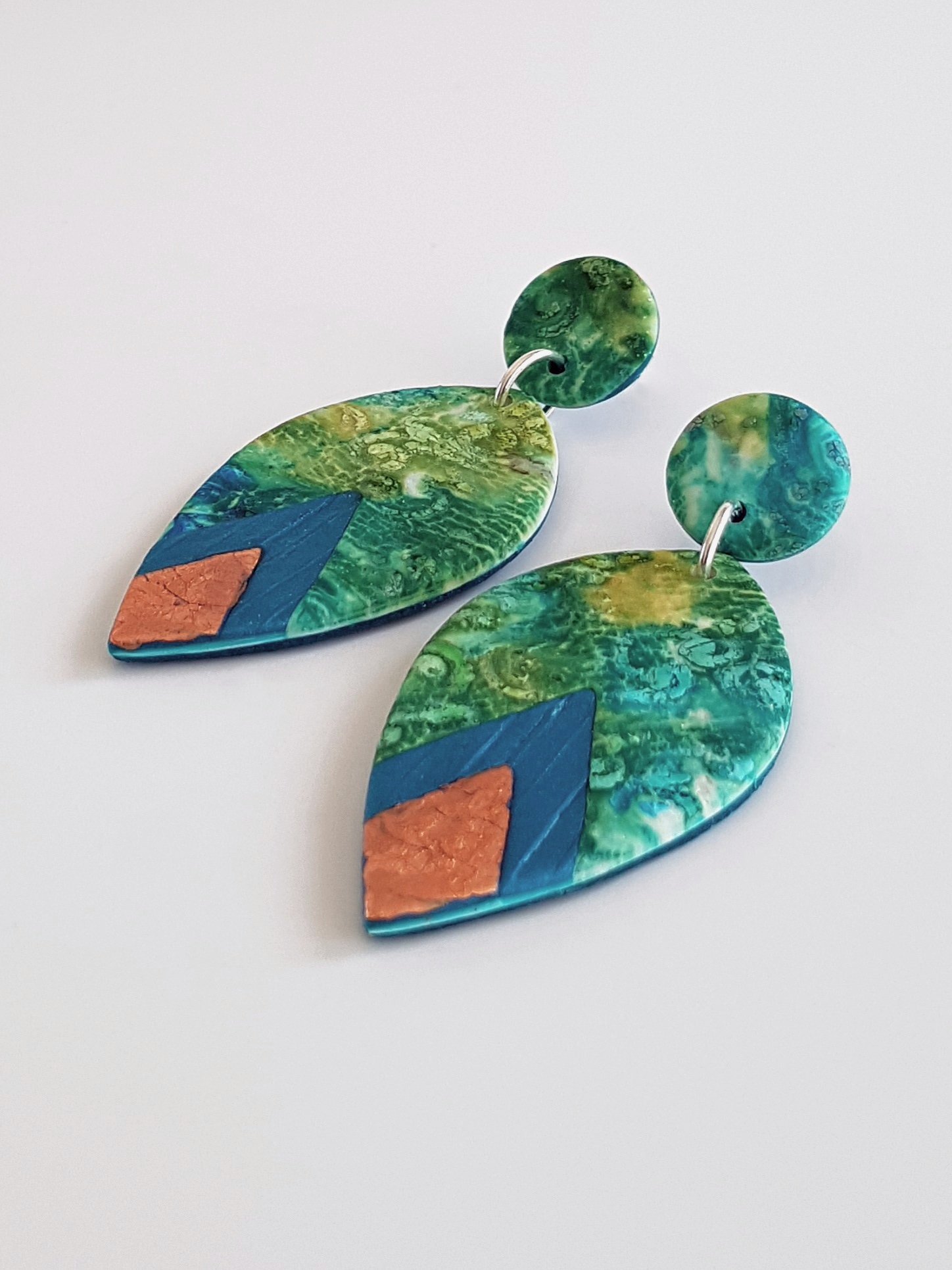 side profile of flat, teardrop bead earrings, with faux bronze and peacock diamond shape accents. Round stud tops.