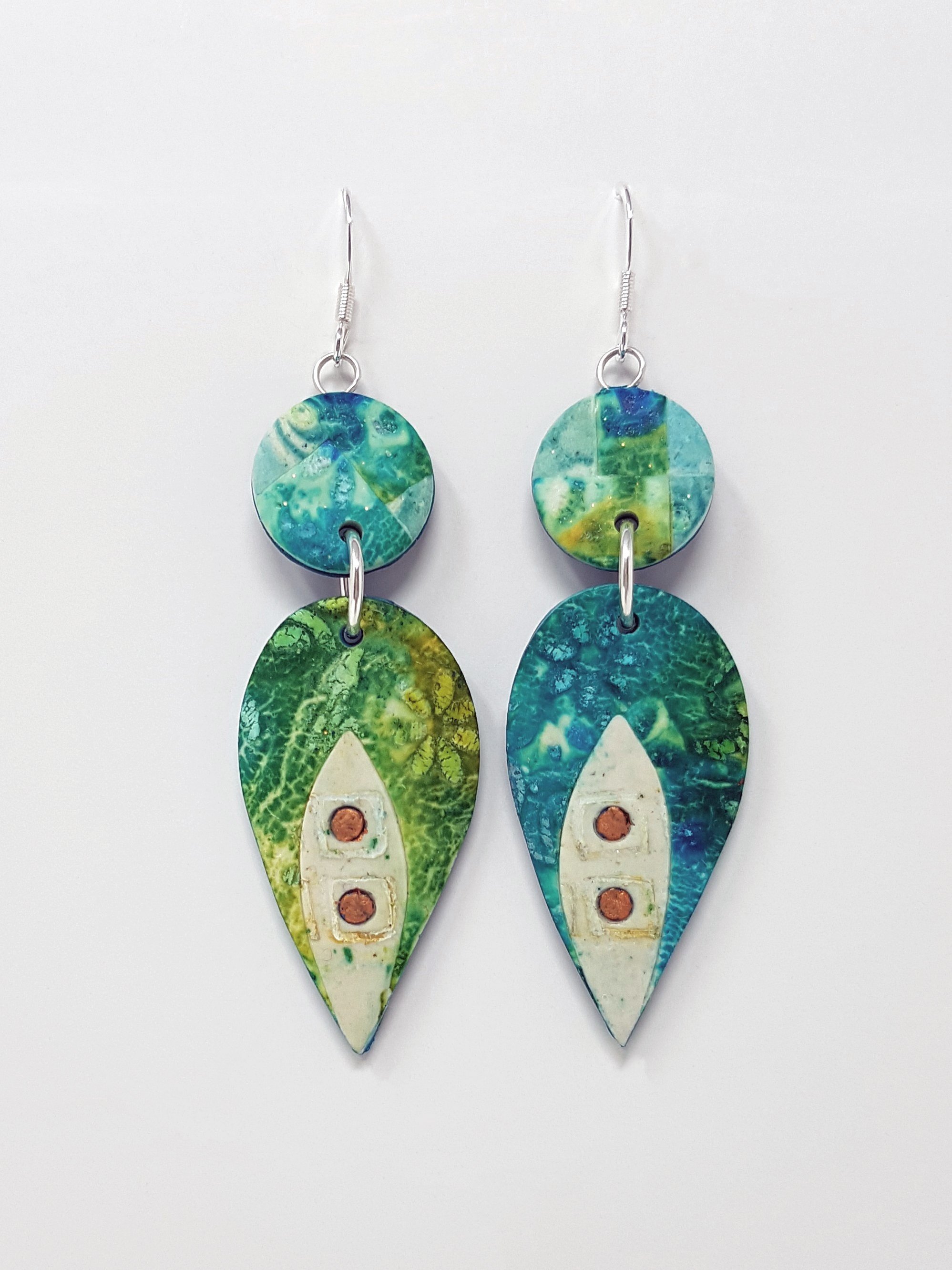 Long earrings with mosaic pattern upper bead and inverted teardrop lower bead in peacock greens and blues. Bronze dot accents on cream petal inlays.