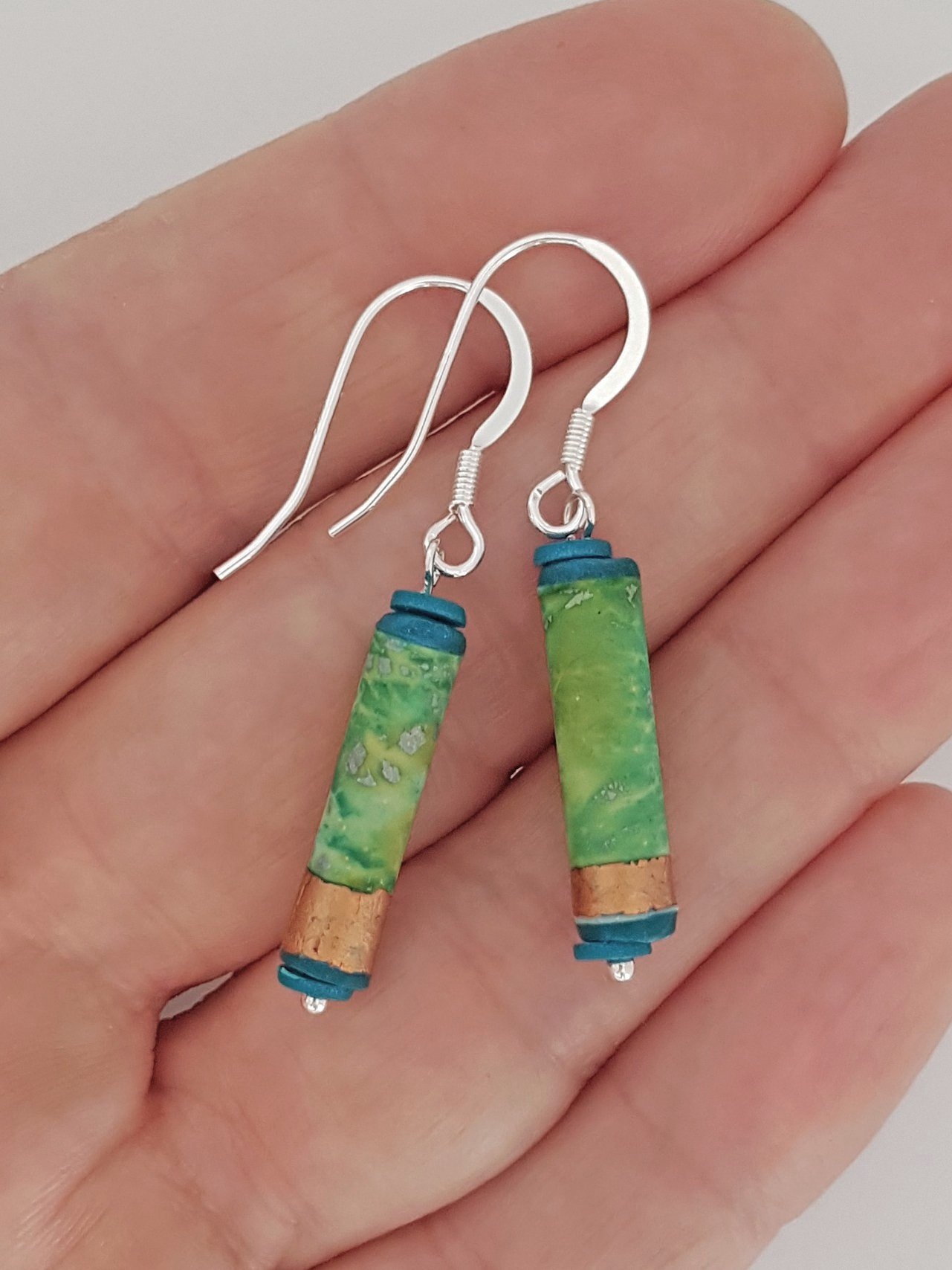 Turquoise, green, blue sealed tube style earrings, sterling silver ear wires in palm of hand.