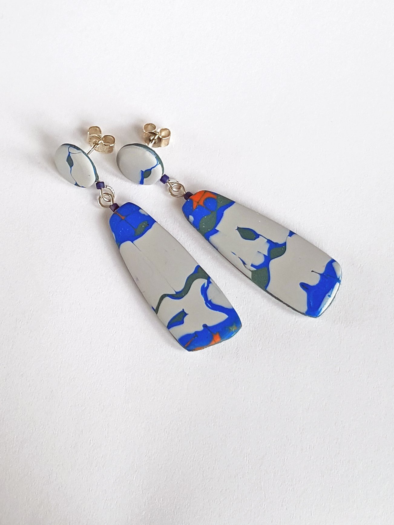 Earrings with abstract 1950's style line and curve pattern in grey, red, green and blue, with subtle convex profiles to the dangle beads.