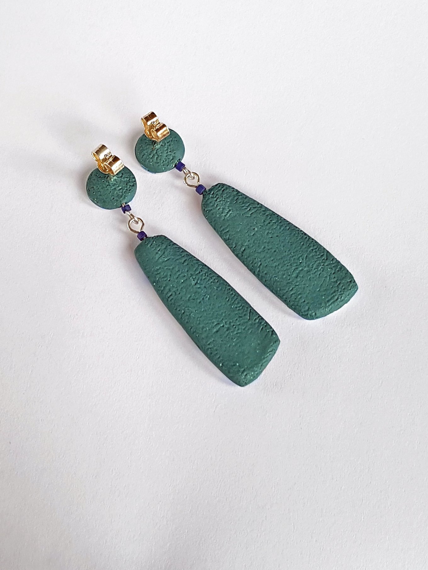 The backs of Frequency Grey Grey earrings are dark green with sterling silver posts and scrolls.