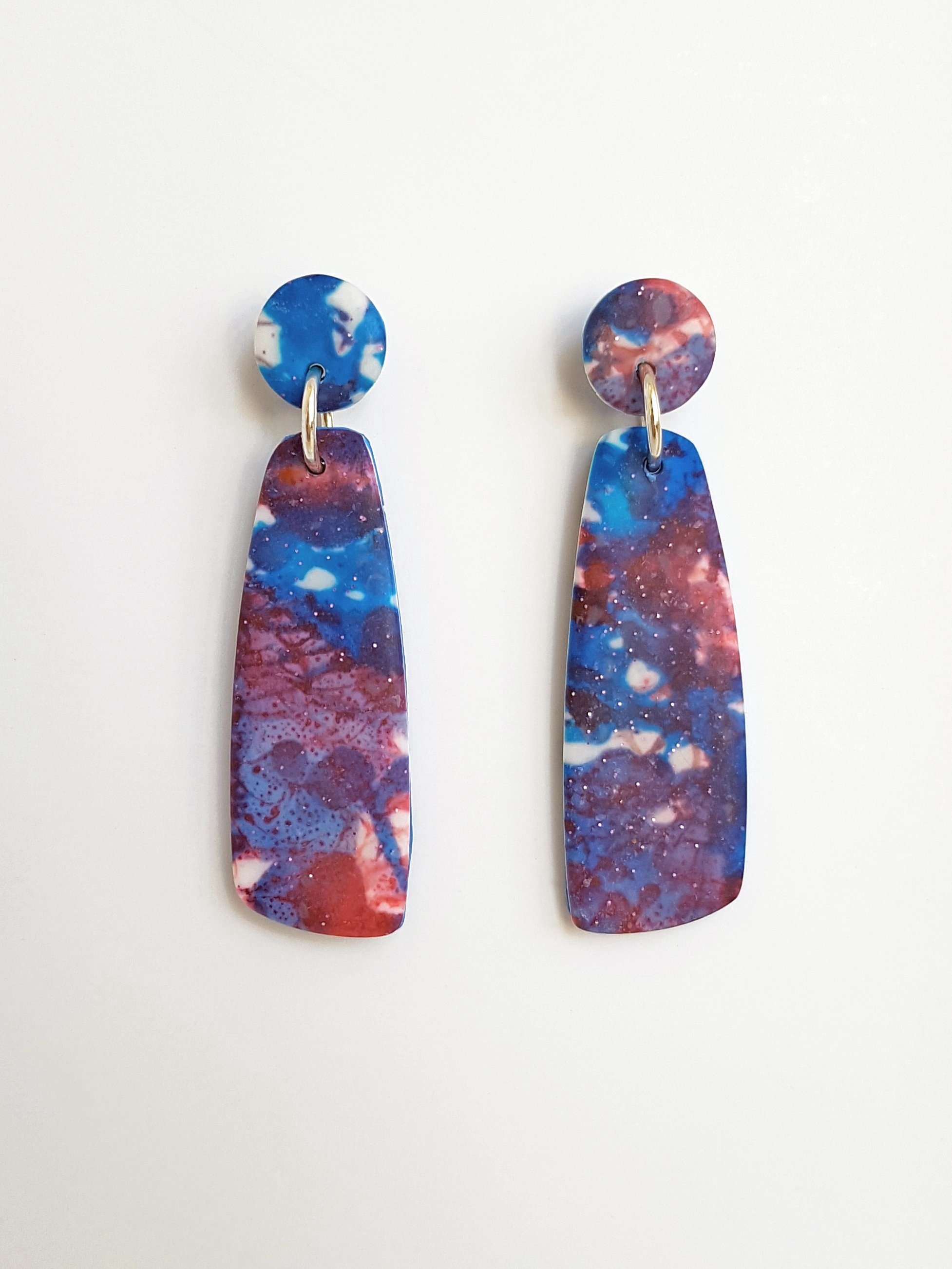 Blue, red and white mismatched dangle earrings with a matte, line and brushstroke pattern.