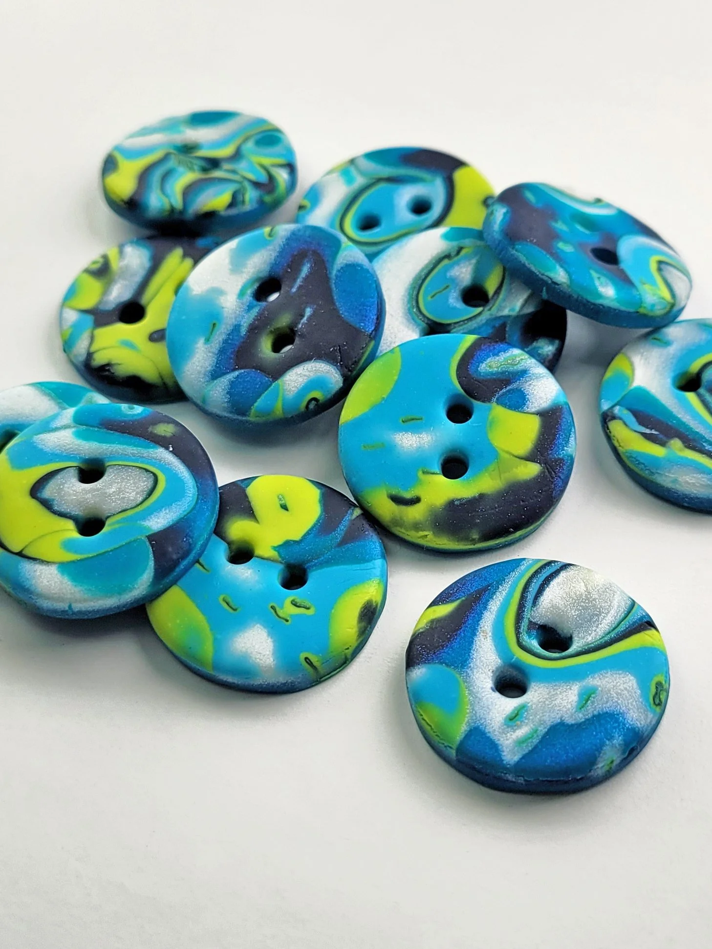 A group of blue, lime and white buttons pictured from the side, lying on a white background, to illustrate their profiles