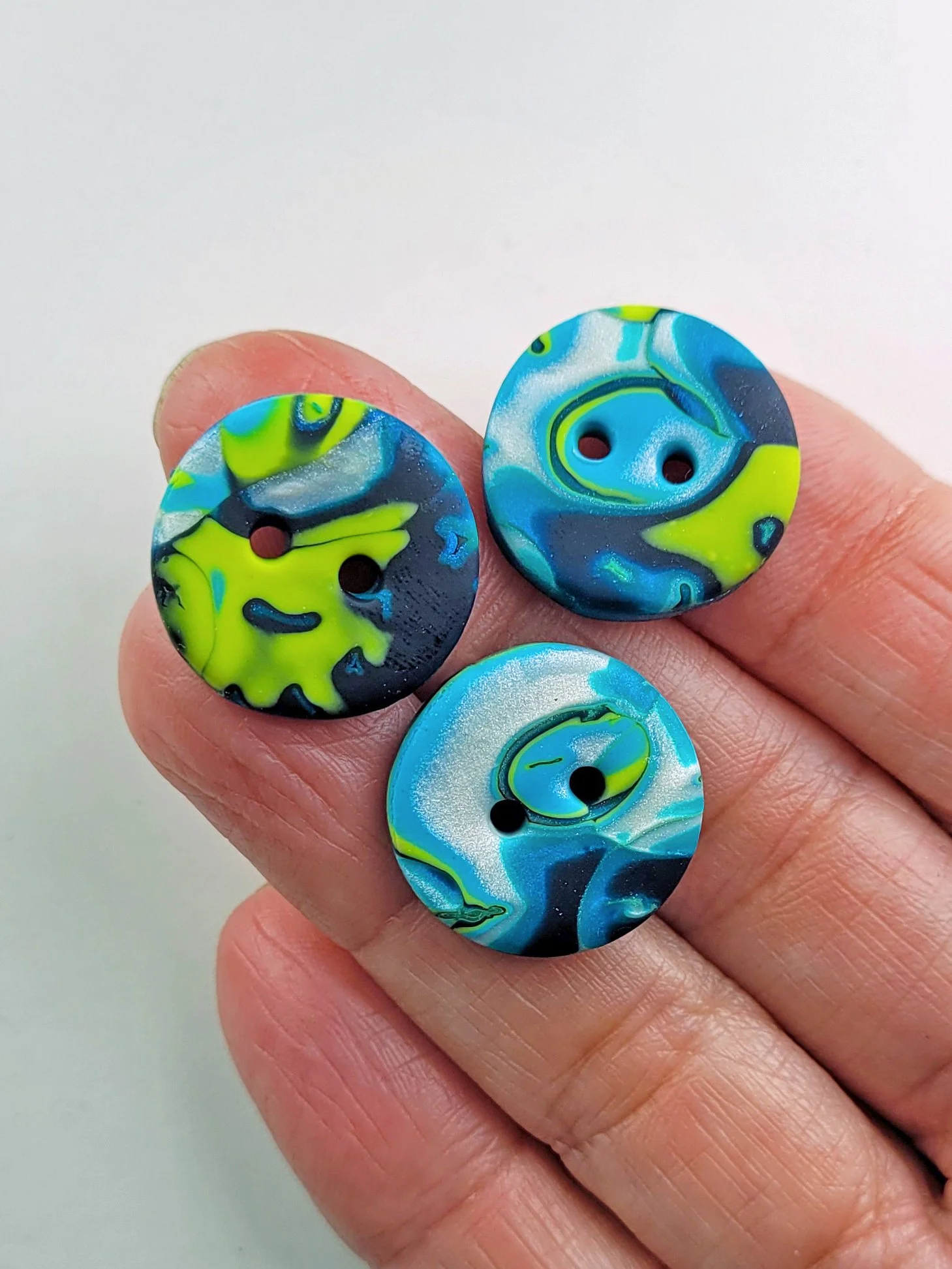 Three buttons lying on a hand to indicate their size