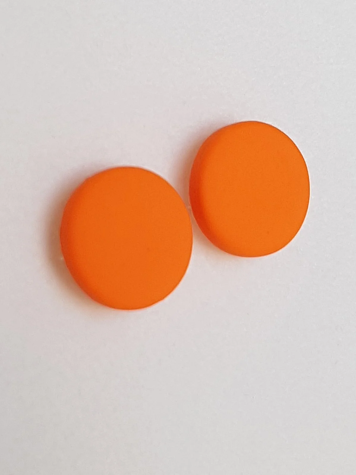 Orange round stud earrings with a smooth matte finish made with polymer clay and sterling silver posts and scrolls.