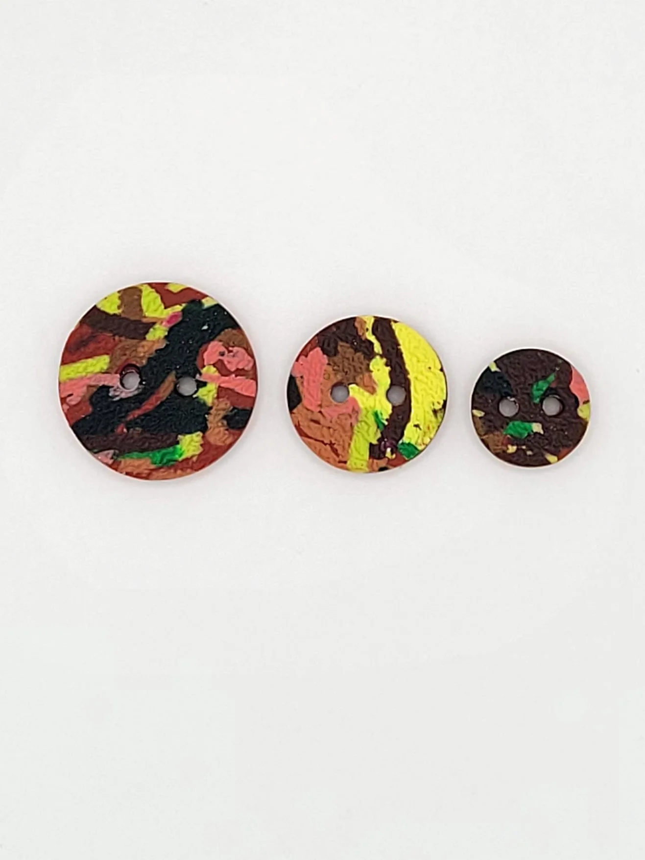 Flat lay of Terracotta Ticker Tape buttons in 3 different sizes.