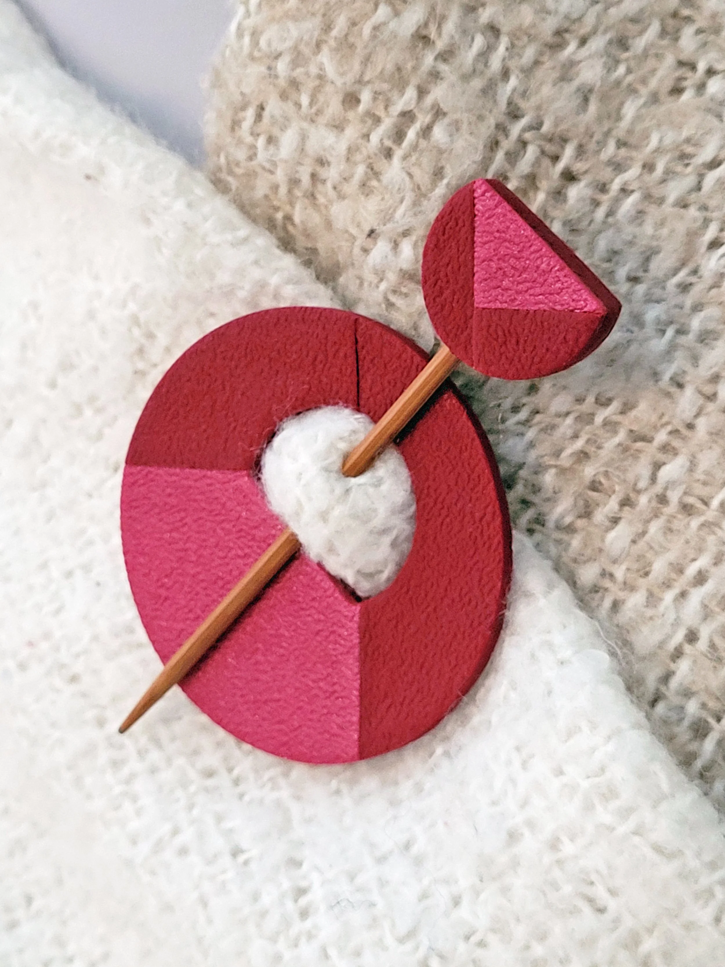 The decorative dark red pin head features a geometric half circle with a pearlescent pink triangular accent.