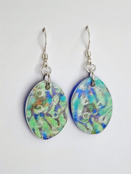 Side view of flat, elliptical bead dangle earrings emphasizing their oval shape and pastel floral pattern.