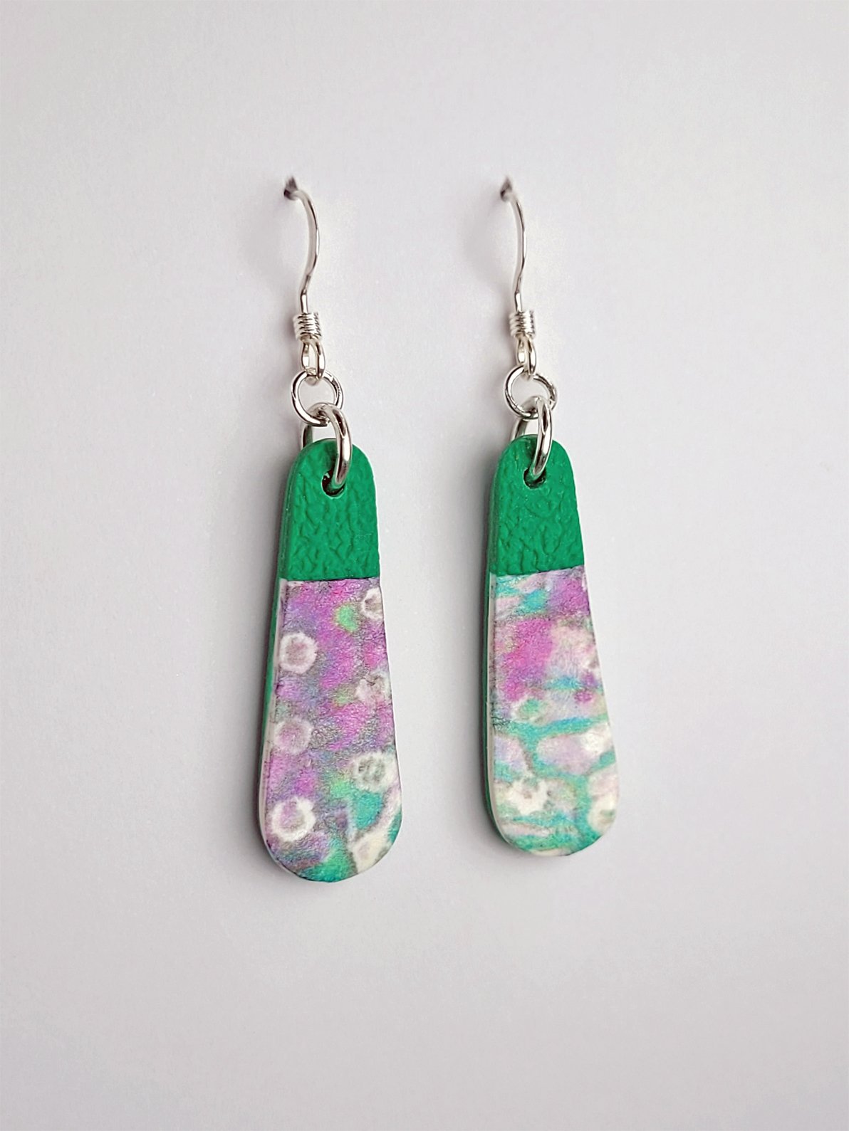 Side view of teardrop earrings with patterned upper layer, contrasting with the textured green tips and backs.