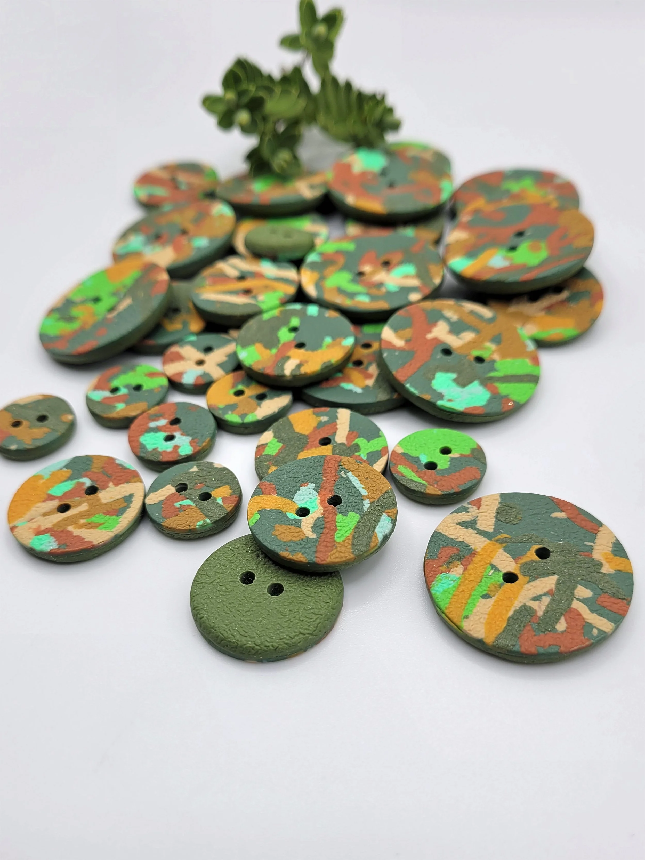 Green Ticker Tape buttons scattered on a white surface with a small green plant the background
