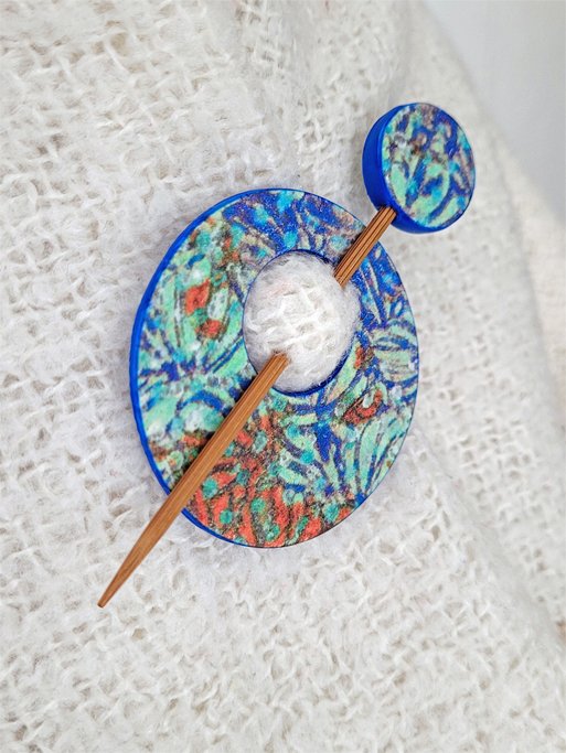 Edge of pin, highlighting the decorative abstract foliage pattern and contrasting blue polymer clay back.