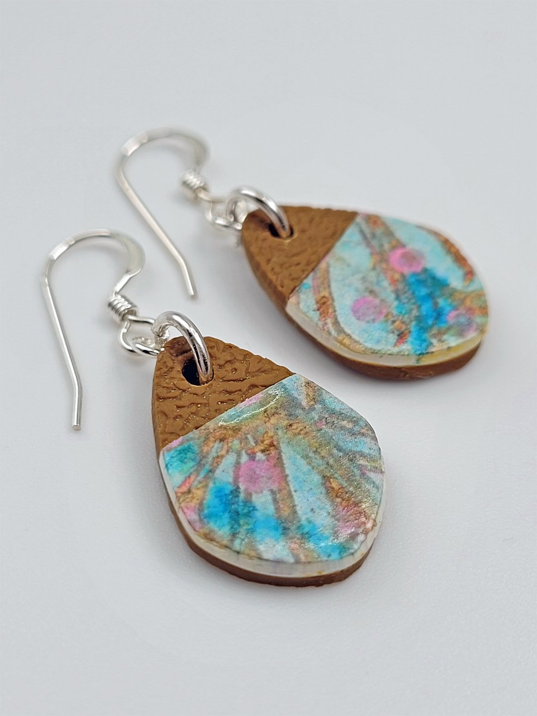Flat lay of mini 'fat' teardrop earrings highlighting their contemporary abstract floral surface pattern design with contrasting matte ginger brown tips.