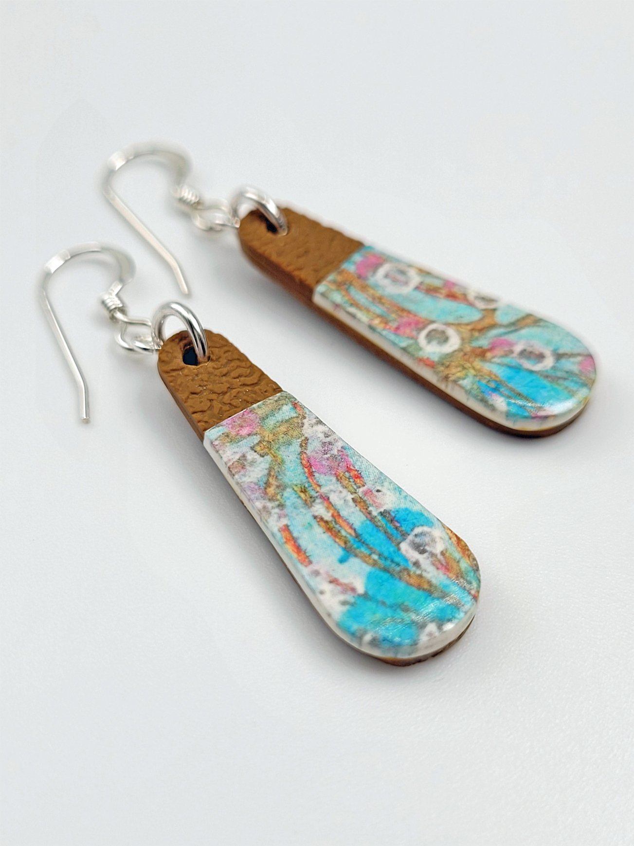 Flat lay of Sprig Ginger Teardrop earrings highlighting their contemporary pastel floral design and elegant shape.