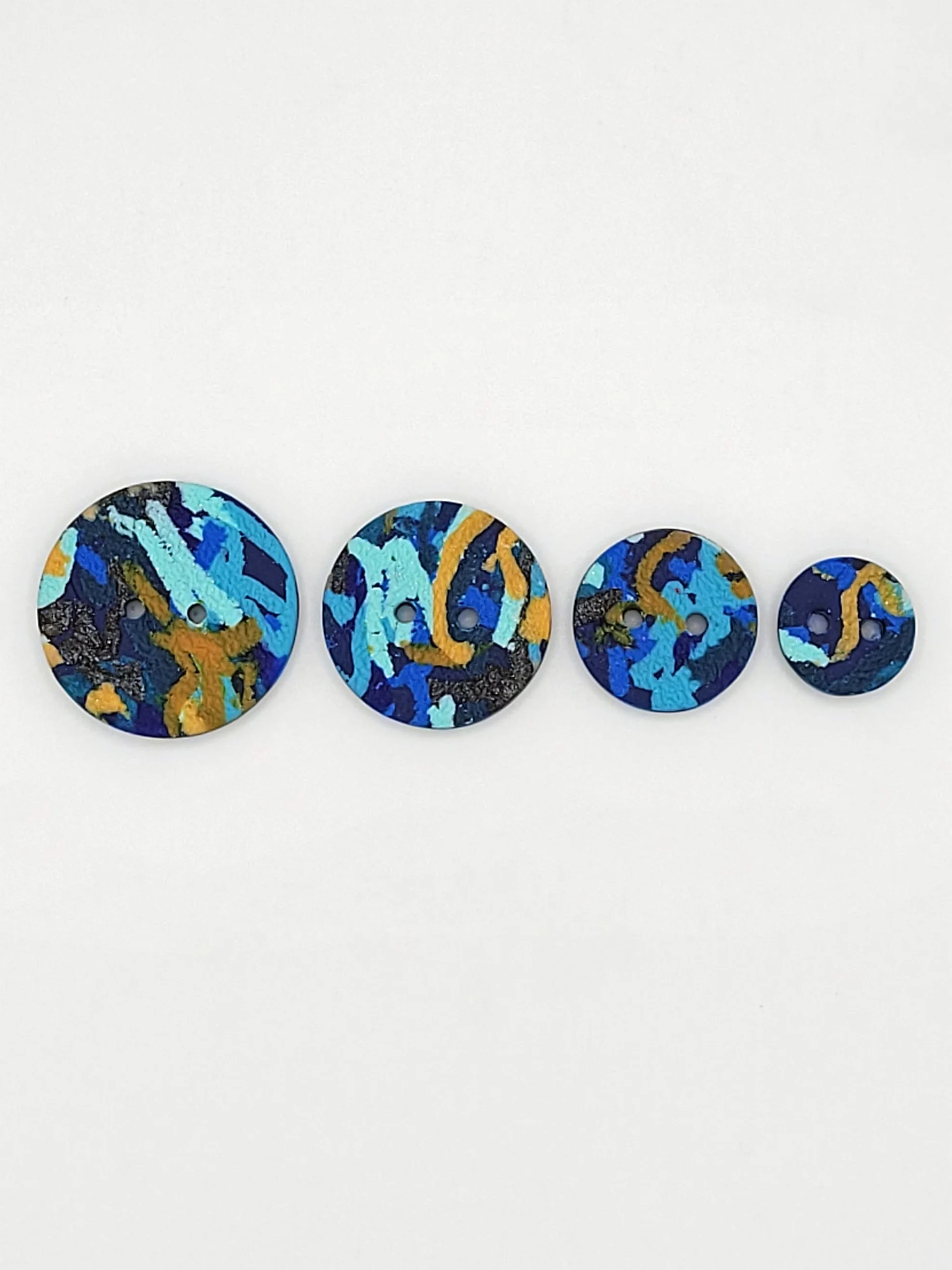 Flat lay of Blue Ticker Tape buttons in 4 different sizes.