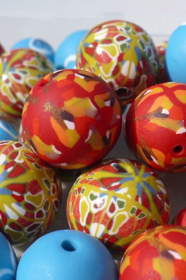 A close up detail of an assortment of beads decorated with different cane patterns and colours.