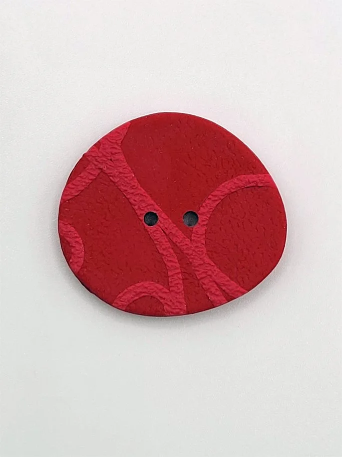 A close-up of a large size Raspberry button in the Pebble Collection.