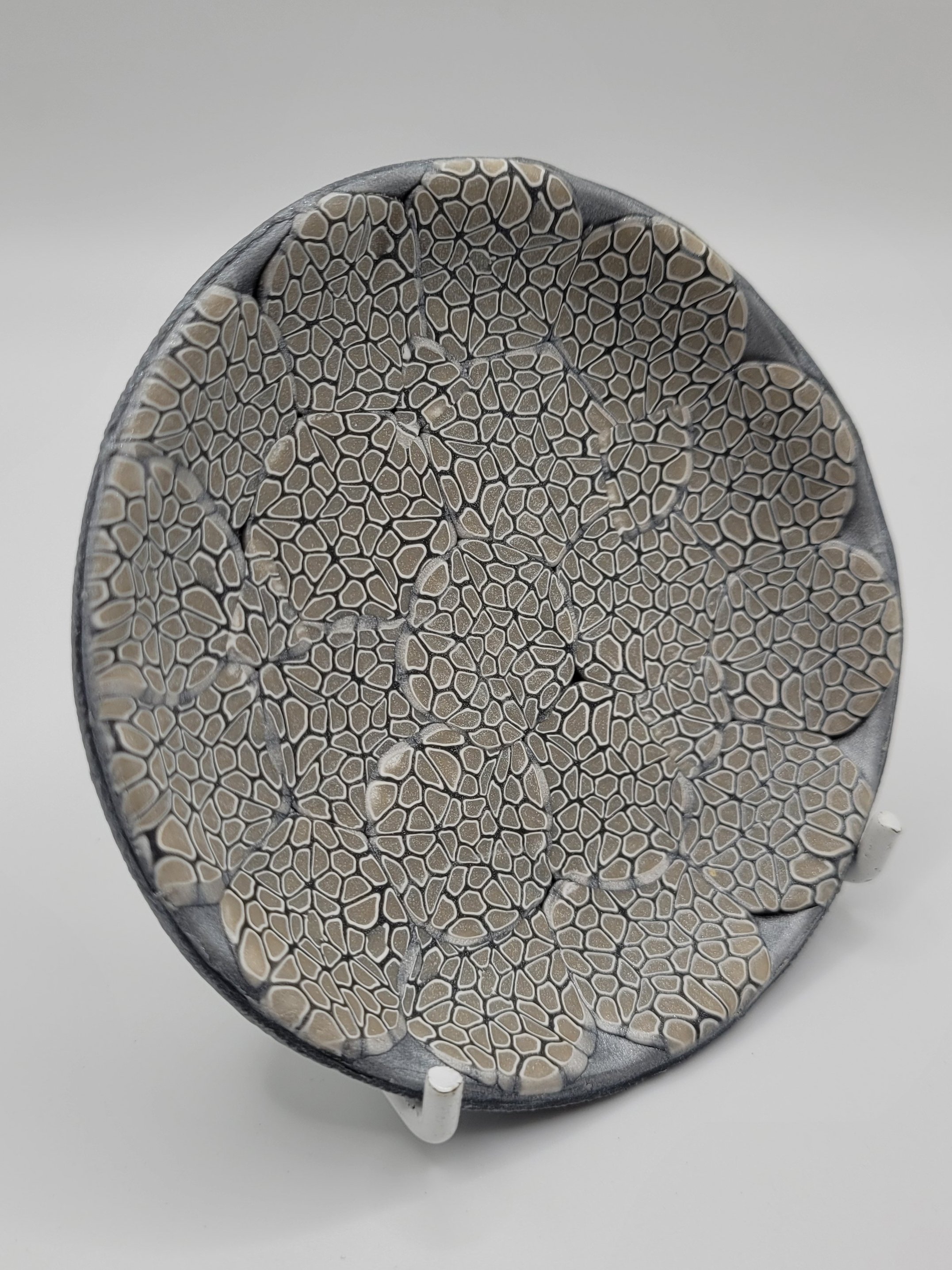 A dish decorated with an elegant millefiori cane in shades of grey
