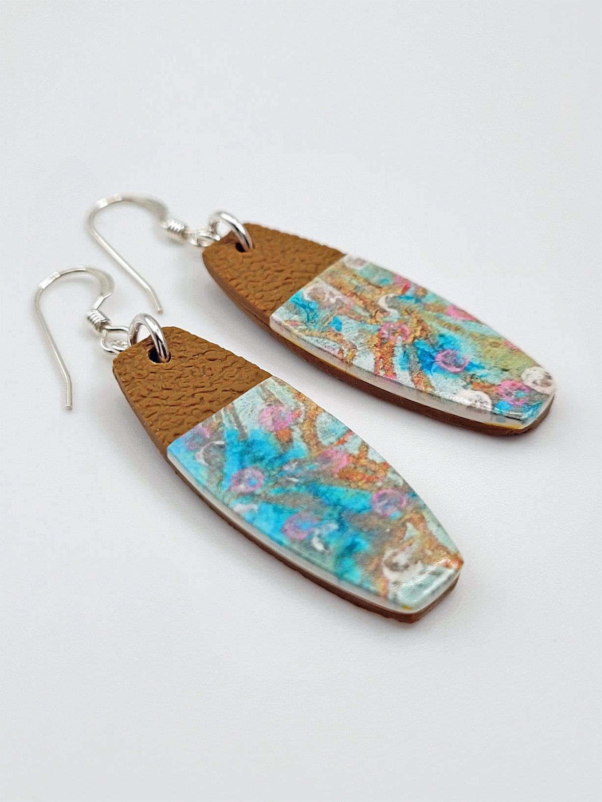 Flat lay of tablet-shaped earrings highlighting their unusual shape and abstract pastel floral design.