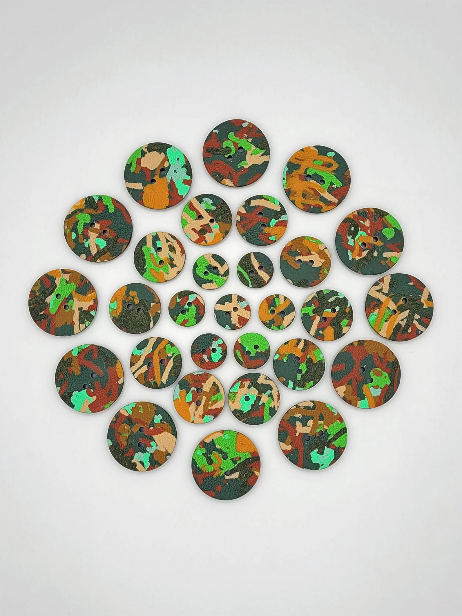 Aerial view of Green Ticker Tape buttons arranged in a circle with the smallest in the middle, getting bigger towards the outer edge of the circle.