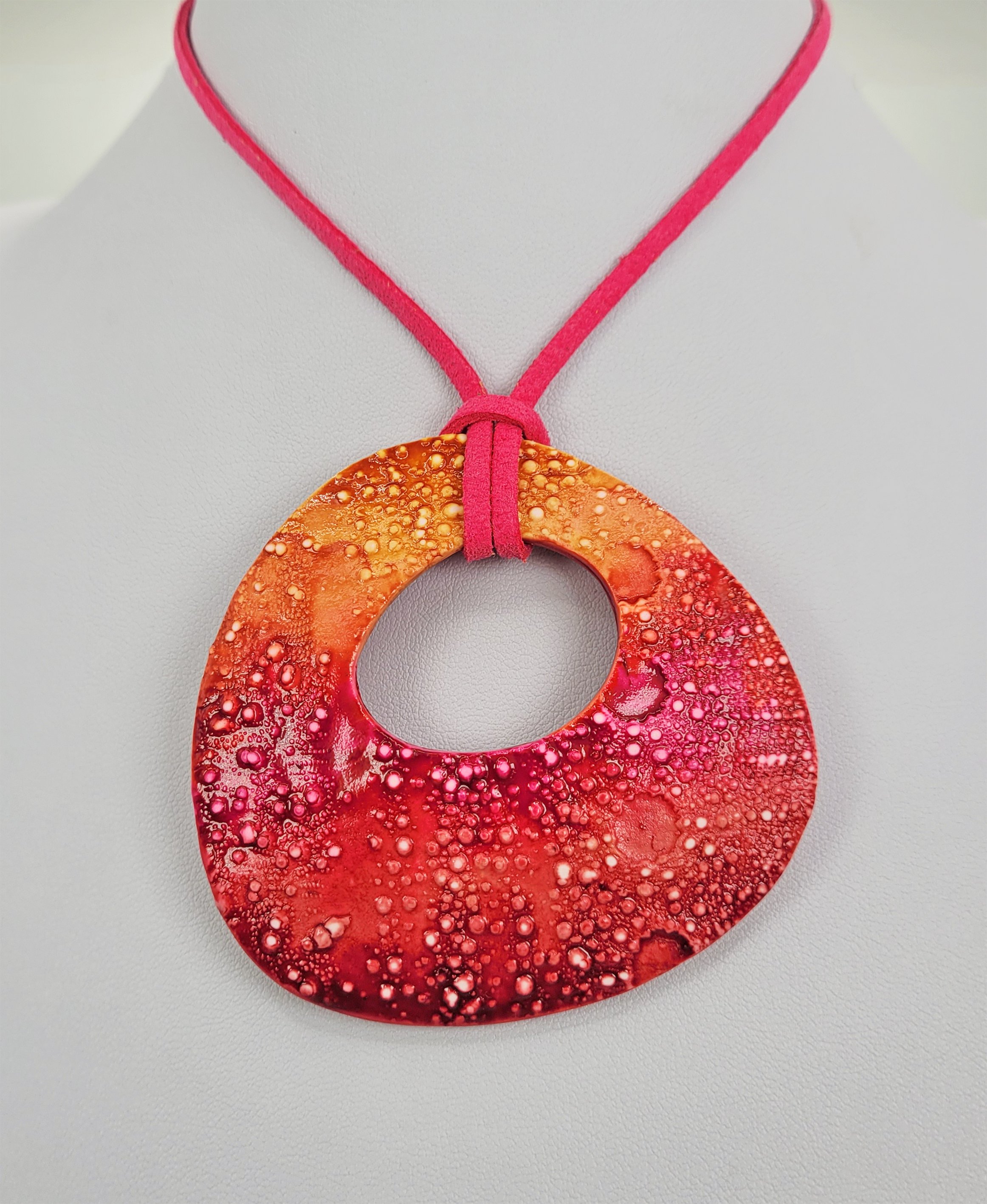 A pink and yellow example of the Sea Urchin shawl pin work as a pendant on a bright pink faux suede cord