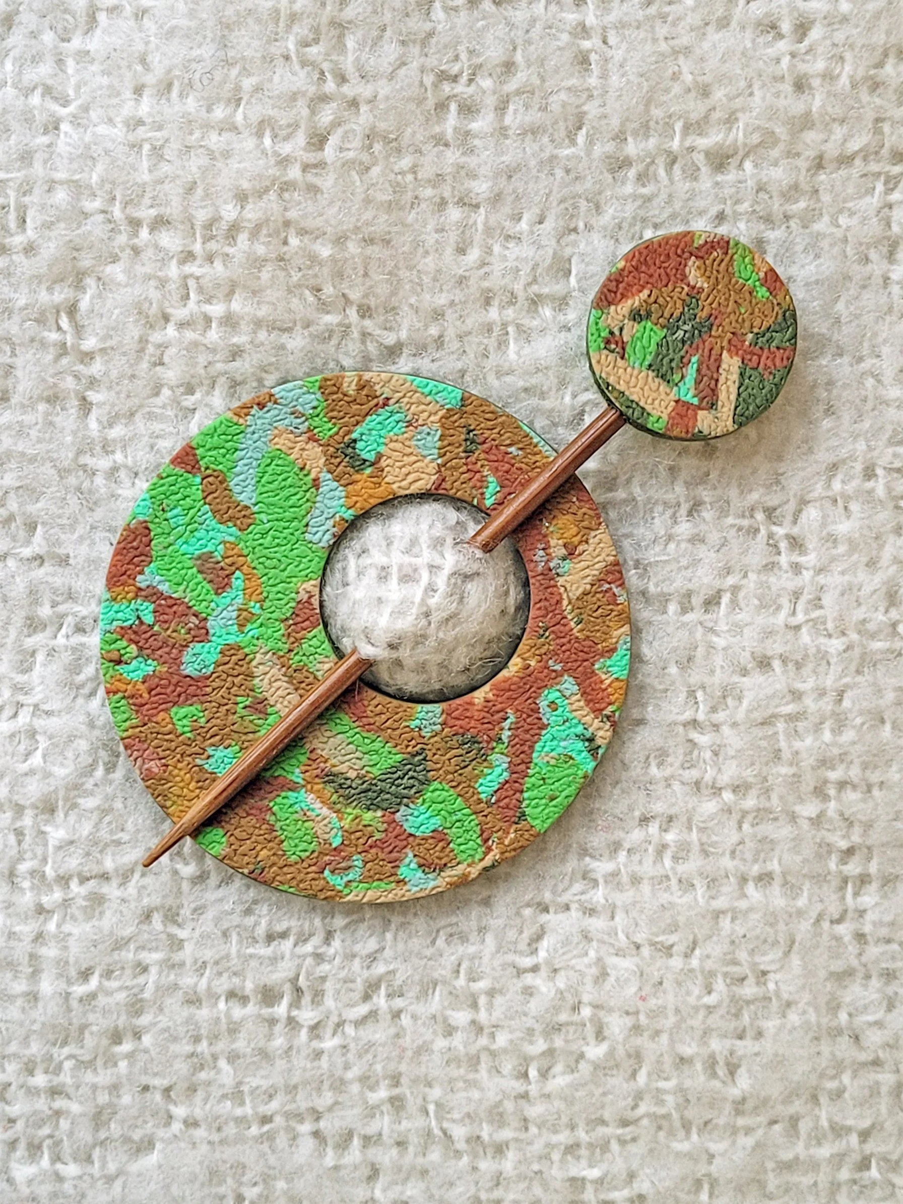 Circular Green Ticker Tape polymer clay shawl pin, with a bamboo pin, topped with a matching round disc.