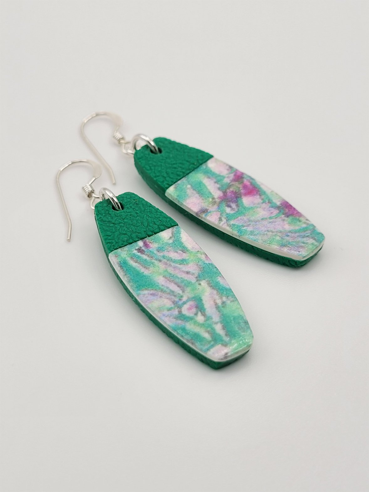 Flat lay of tablet-shaped earrings highlighting their abstract pastel floral design and contemporary look.