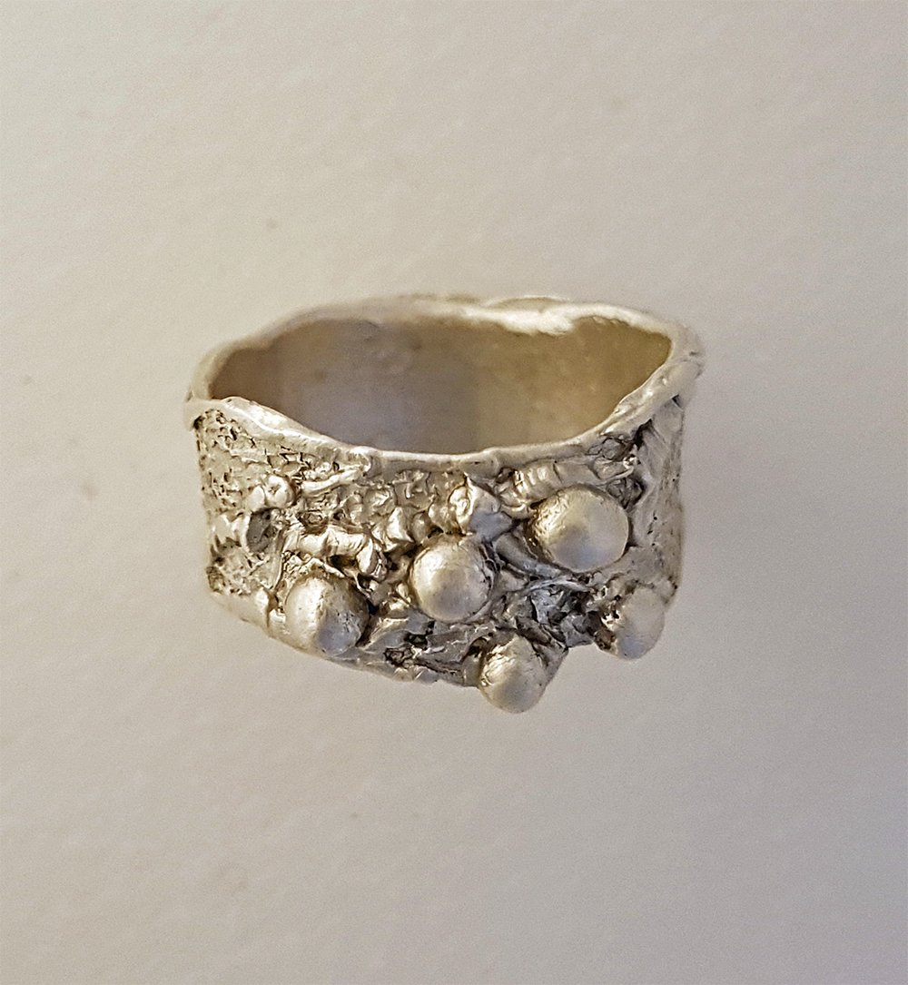 A organic style fine silver ring with irregular edges decorated with lines and beads made by a student on the Silver Ring workshop.